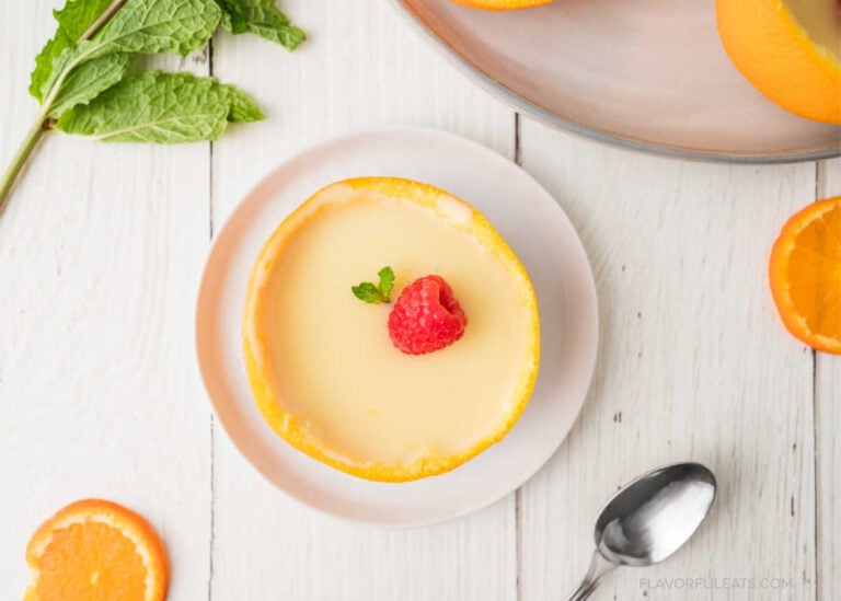 Orange Lemon Posset on a small white plate with a raspberry garnished on top.