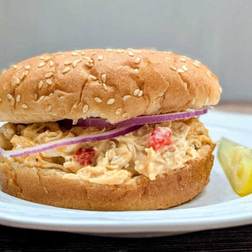 Slow Cooker Pimento Cheese Chicken Sandwich on a plate with a pickle.