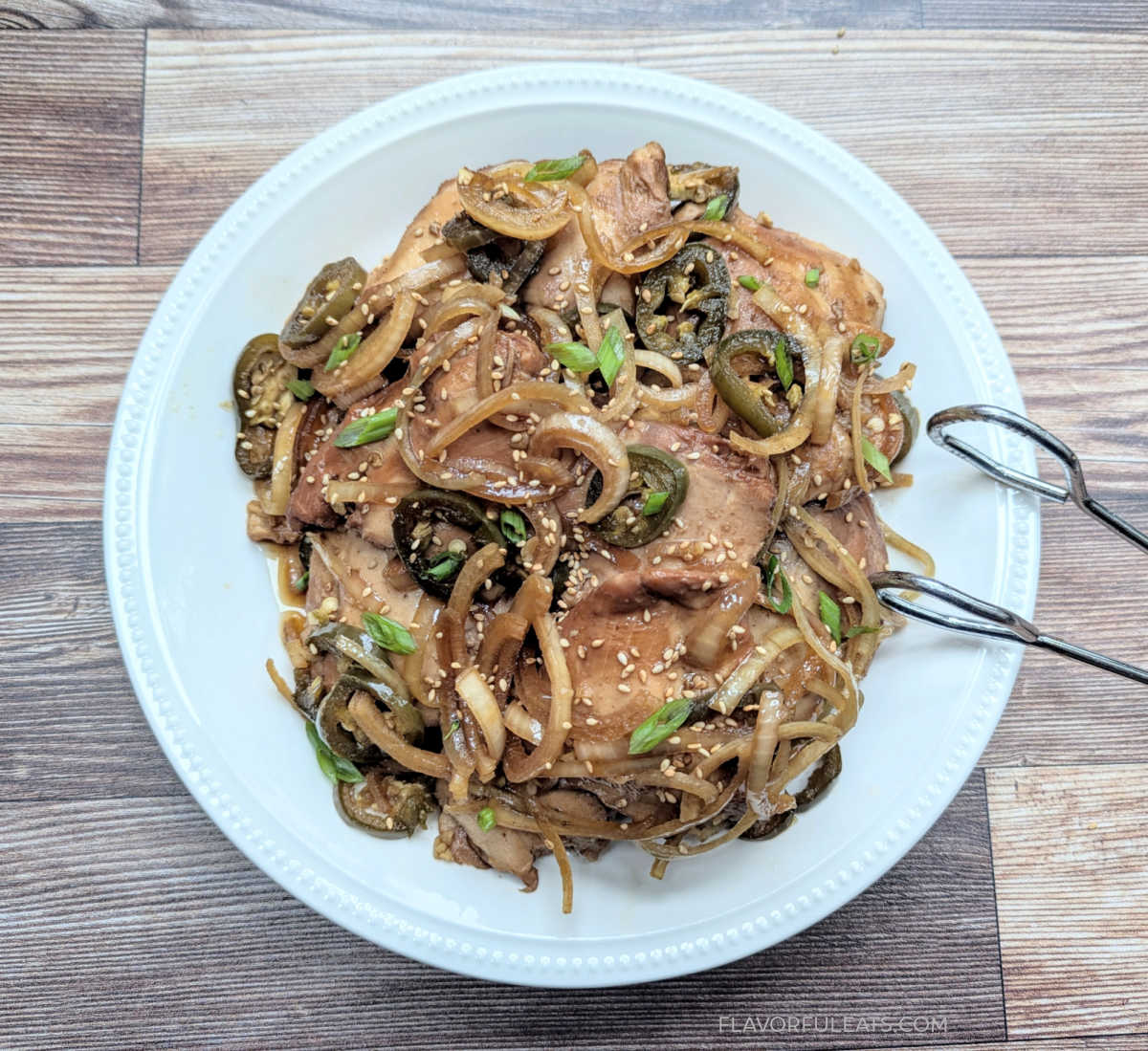 A serving plate of Slow Cooker Soy Jalapeno Chicken with tongs, ready to serve.