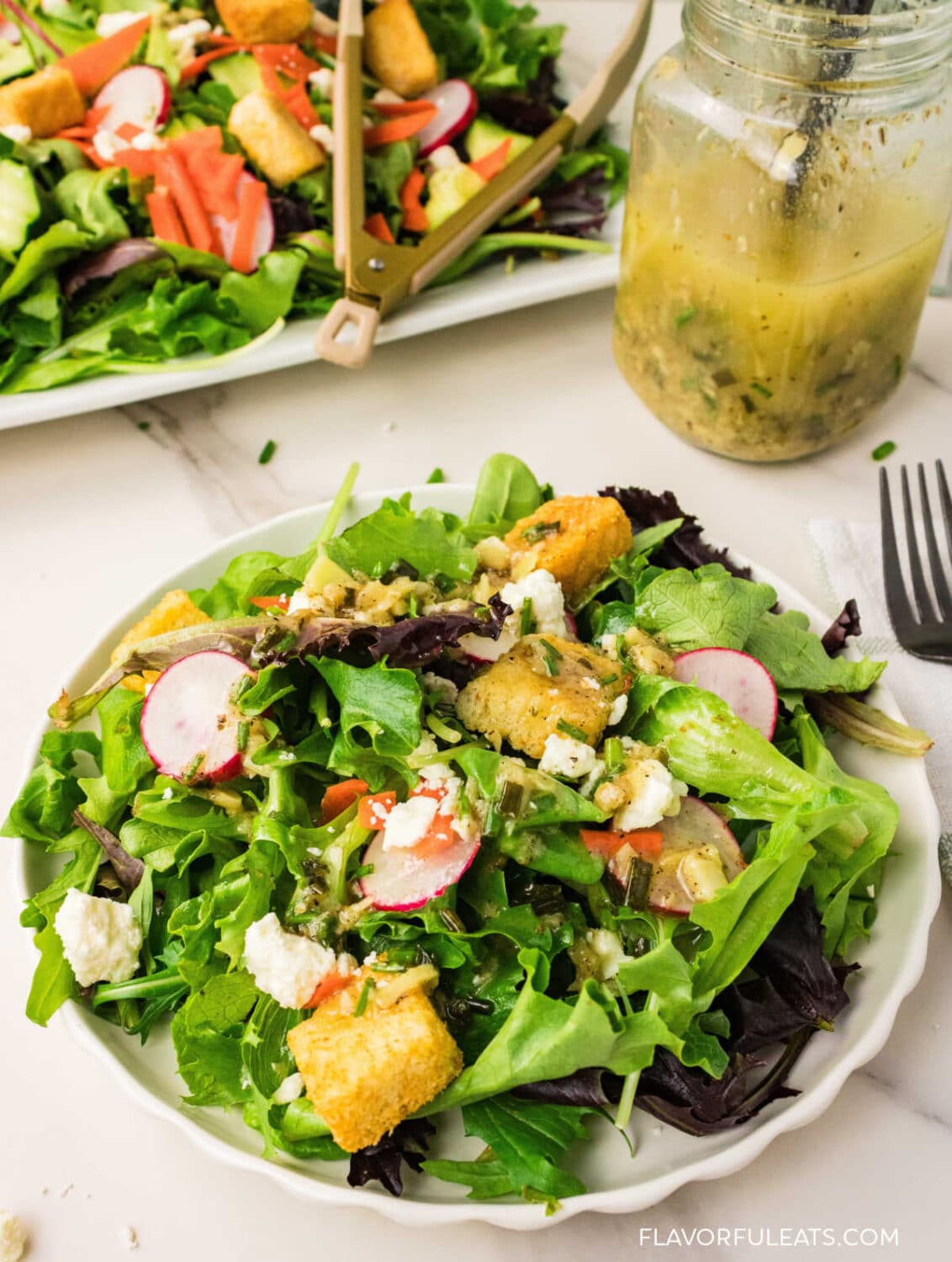 Roasted Garlic Vinaigrette on a salad with the dressing in the jar beside it.