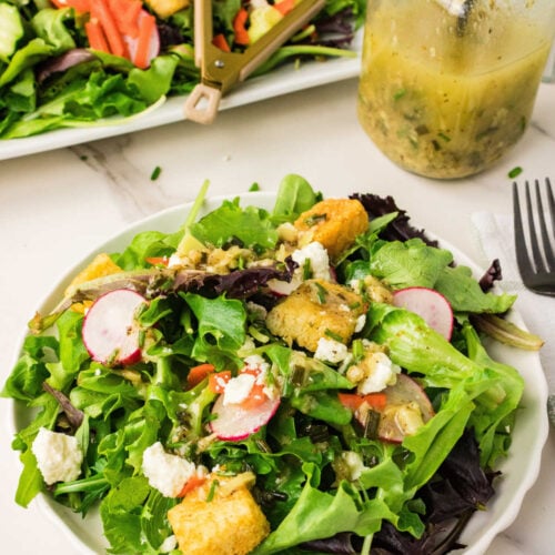 Roasted Garlic Vinaigrette in a jar beside a salad with the dressing on it.