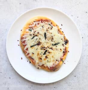 An Air Fryer Mini Naan Pizza on a white plate.