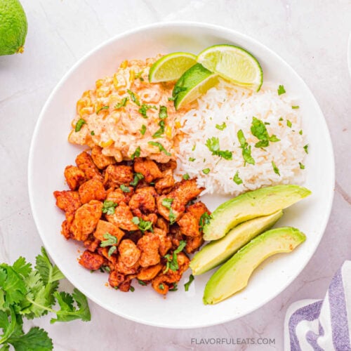 Mexican Street Corn Chicken Bowls in a white bowl with esquites (Mexican street corn), rice, and avocado.