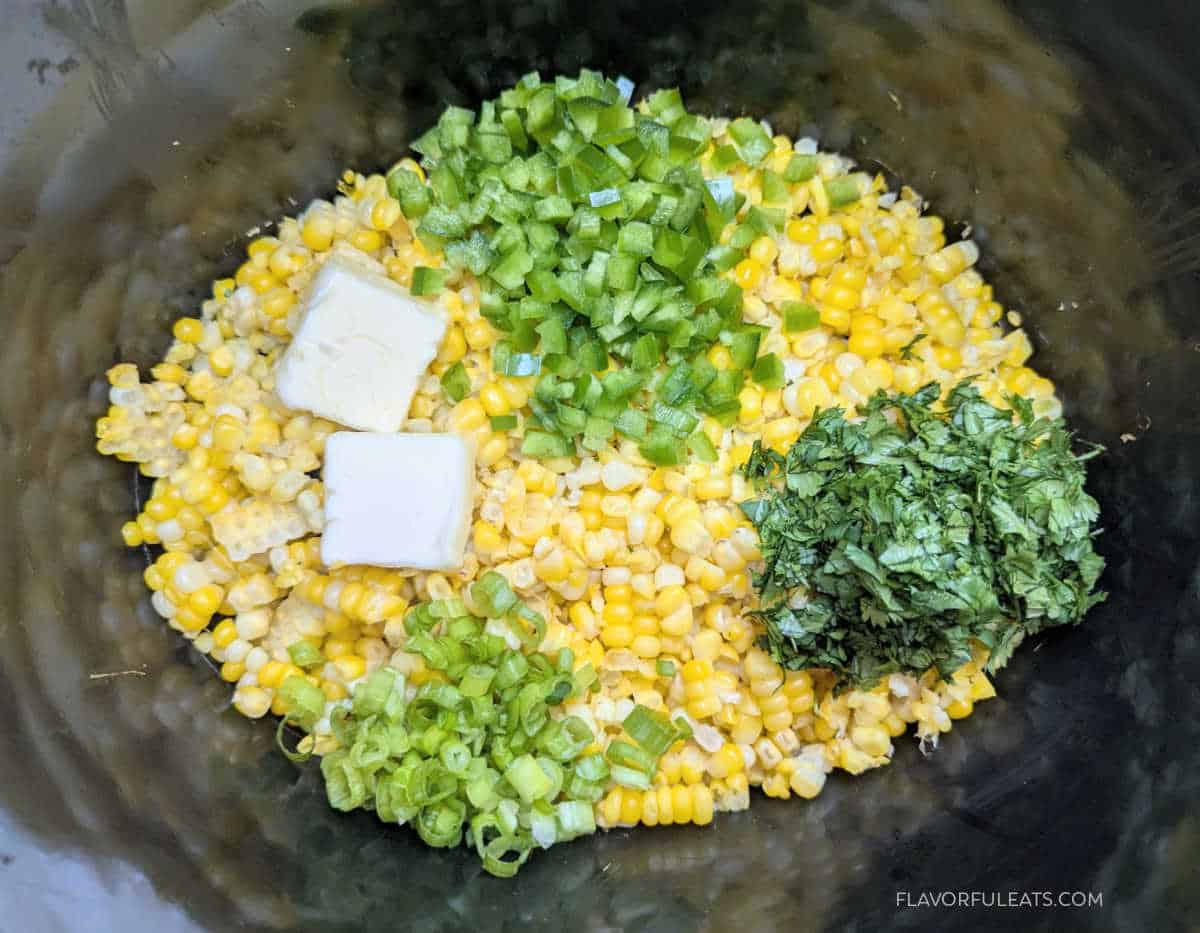 Butter, jalapeno, cilantro, and scallions added to the corn kernels in the slow cooker.