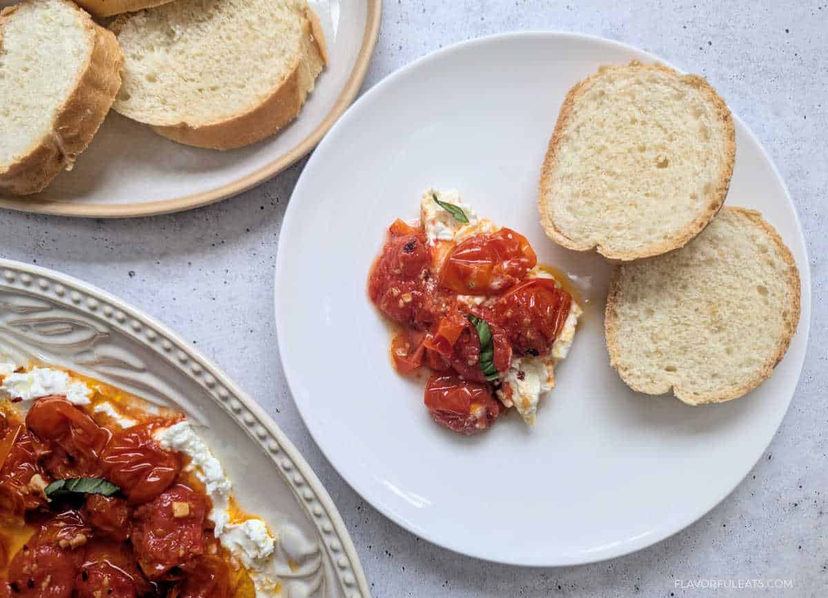 A serving of Roasted Cherry Tomato Goat Cheese Dip on a plate with bread for dipping.