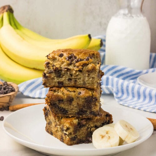 Squares of Chocolate Chip Banana Snack Cake stacked on a plate.